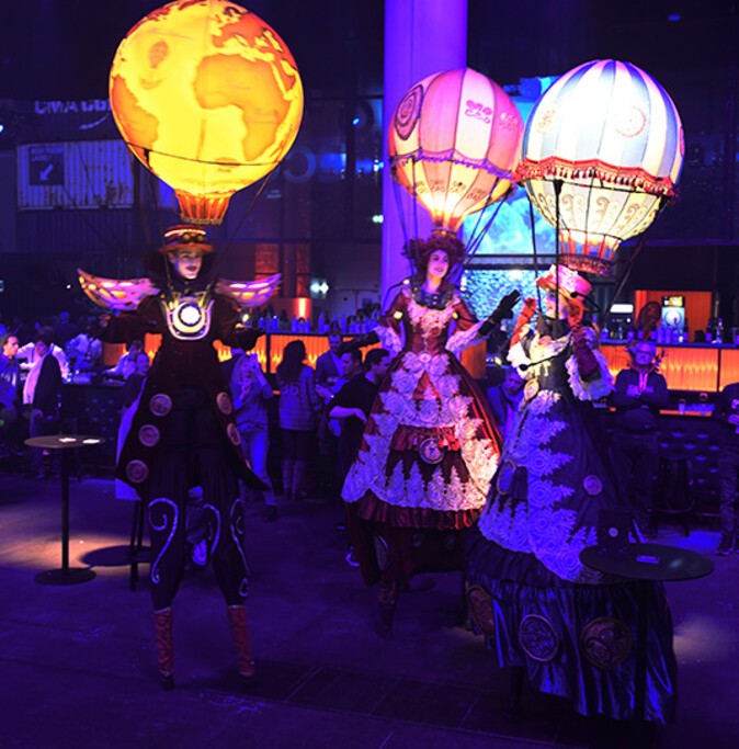 Three people in costumes walking on stilts 