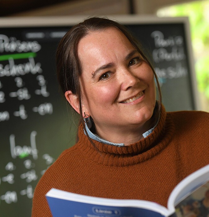 Portrait of Irene Tagmi holding a book, with the whiteboard in the background