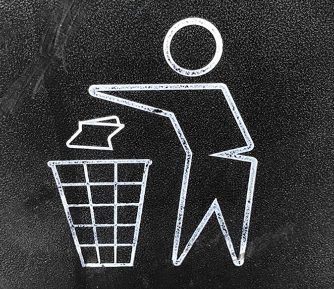 A pictogram of a man throwing something into a rubbish bin