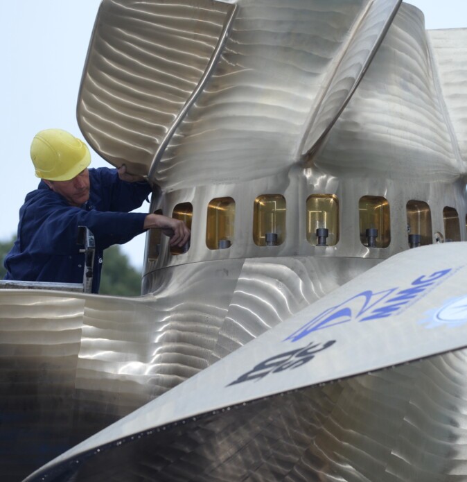 A worker screws on a ship's propeller