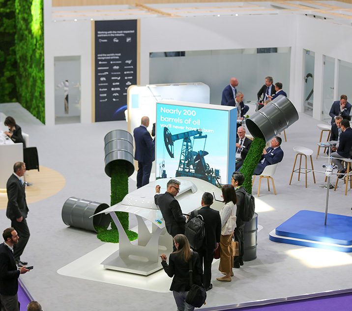 An exhibition stand all in white with people looking at a technical exhibit.