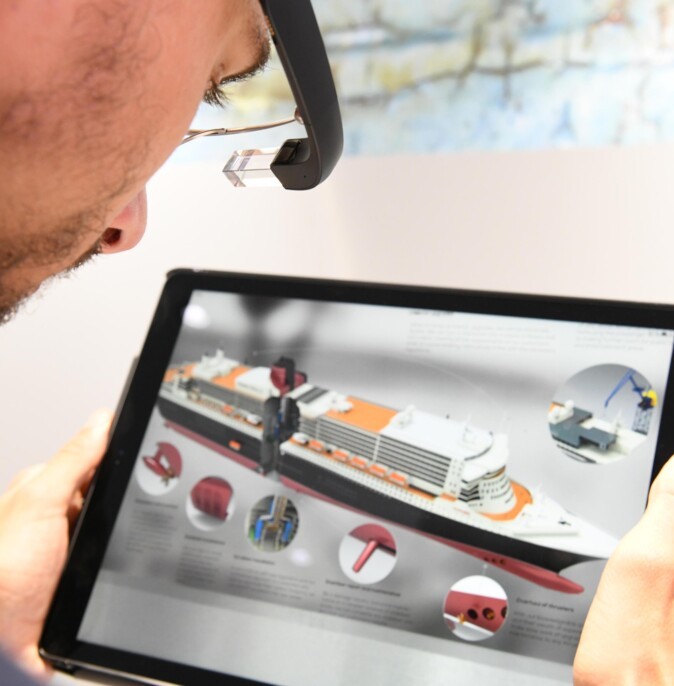 A man looks at a model of a ship on a tablet